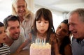 Six year old white girl blowing out the candles on birthday cake watched by her family, close up Royalty Free Stock Photo