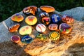 Sixteen painted rocks on a boulder in afternoon sun