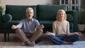 Sixties couple meditating sitting in lotus pose on floor