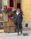 Sixty-five year-old female Korean tourist enjoying a sidewalk flower display in Pitigliano, Italy.