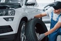 Size comparison. Mechanic holding a tire at the repair garage. Replacement of winter and summer tires Royalty Free Stock Photo