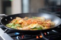 sizzling kimchi pancake cooking on gas stove