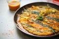 sizzling kimchi pancake in oil, bubbles forming on edges