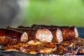 Sizzling sausage meat on a campfire barbecue. Royalty Free Stock Photo