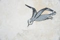 Skadovsk, Ukraine - June 15, 2017: Bird in flight, drawing on an old wall of whitewashed lime, background, retro drawing since uss