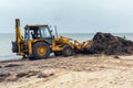 Skadovsk, Ukraine, June 18, 2021: Cleaning the beach from algae using an excavator