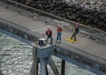 Three dock workers hauling ropes to secure cruise ship to bollards