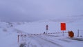 Closed gate at road to popular Nordkapp (North Cape) in winter with orange sign informing about the convoy hours. Royalty Free Stock Photo