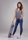 Skate betty. Full length studio portrait of casually-dressed young woman holding on a skateboard.