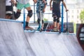 Skate park view with kids on a kick scooter doing tricks and stunts, boys in a skate park riding bmx bike and skate, playing and Royalty Free Stock Photo