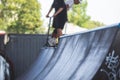 Skate park view with kids on a kick scooter doing tricks and stunts, boys in a skate park riding bmx bike and skate, playing and Royalty Free Stock Photo