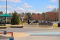 A skate park with young men riding skateboards surrounded by yellow winter grass, green umbrellas over benches