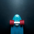 Skateboard with blue deck and red wheels on black background with copy-space top view. Concept of sport lifestyle, culture, leisur