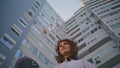 Skateboard girl standing city building bottom view closeup. Curly hipster posing Royalty Free Stock Photo