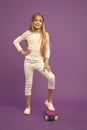 Skateboard kid in casual wear on violet background. Girl skater smiling with longboard. Small child smile with skate Royalty Free Stock Photo