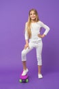 Skateboard kid in casual wear on violet background. Girl skater smiling with longboard. Small child smile with skate Royalty Free Stock Photo