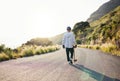 Skateboard, road walking and athlete doing training, exercise and fitness on a hill. Sun, man back and summer sport of a Royalty Free Stock Photo