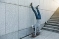 Skateboarder doing a handstand on skateboard against wall