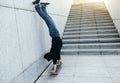 Skateboarder doing a handstand on skateboard against wall