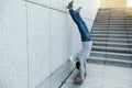 Skateboarder doing a handstand on skateboard against wall