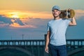 Skateboarder holding skate on his shoulder against the backdrop of a beautiful sunset, free space. Royalty Free Stock Photo