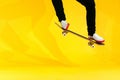 Skateboarder performing skateboard trick - ollie on concrete. Studio shot of olympic athlete practicing jump on yellow background