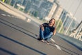 Skateboarder sitting on his skateboard at highway bridge