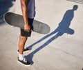 Skateboarding, sport and man holding a board for fun, riding and playing at a park. Legs, shadow and cool skater or