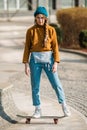 Skateboarding Woman In The City. Skater girl in denim is riding her board on the square. Athletic Woman skateboarder. Building on Royalty Free Stock Photo