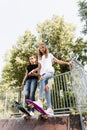 Skater children girls reade to ride on penny board on skate sport ramp at sunset together. Sports equipment for kids