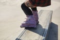 Skater girl grinding on a ledge in a skatepark. Feet of aggressive inline roller blader performing a bs full torque grind in close