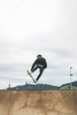 Skater jumping high in the air with a snakeboard in a skatepark with white sky in the background. copyspace Royalty Free Stock Photo