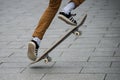 Skater legs wearing black sneakers by Adidas jumping with skate board in the street