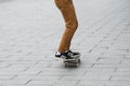 Skater legs wearing black sneakers by Adidas rolling on skate board in the street