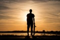 Skater standing on road against the sunset and holding a skateboard in one hand Royalty Free Stock Photo