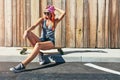 Skaters have more fun. a young woman sitting on her skateboard on a sidewalk. Royalty Free Stock Photo