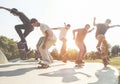 Skaters jumping with skateboard in city suburb park - Sporty guys performing tricks and skills at sunset in urban contest -