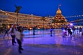 People ice skating at an outdoor arena during the holidays