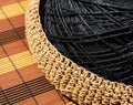 A skein of black raffia in a woven bowl of beige raffia