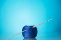 Skein of blue wool yarn for knitting and knitting needles on bright blue background Royalty Free Stock Photo