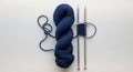 A skein of dark blue yarn is placed next to two silver knitting needles. The yarn is Royalty Free Stock Photo