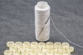 Skein of white thread and a sewing needle. Plastic shiny buttons for clothes on a fabric background. Fashion and clothing