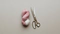 A skein of yarn and a pair of scissors are placed on a neutral gray surface Royalty Free Stock Photo