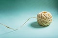 A skein of yellow twine with a loose thread on a light green background