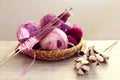 Skeins of multicolored yarn in purple tones, knitting needles on a decorative tray, a branch of cotton on a light table, gray Royalty Free Stock Photo