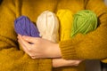 Skeins of yarn of various colors in hands in a in a mustard wool sweater.Wool yarn in yellow, beige, purple and green Royalty Free Stock Photo