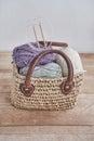 Skeins of yarn, wooden circular knitting needles in handmade straw basket on wooden table Royalty Free Stock Photo