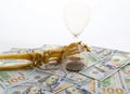 Skeleton fingers holding sand-glass placed on dollars. concept of time - money and death. Royalty Free Stock Photo