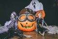 Skeleton, a ghost, a jack o lantern and fake spider webbing on top of a wooden table against a black background Royalty Free Stock Photo