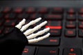 Skeleton hand ready to work on computer, laptop gaming keyboard